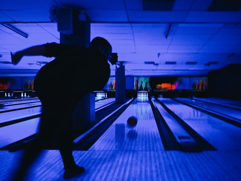 a man throwing a bowling ball down a bowling lane